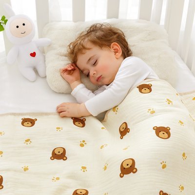 Bébé dormant paisiblement avec une couverture bébé en coton bio motif ourson