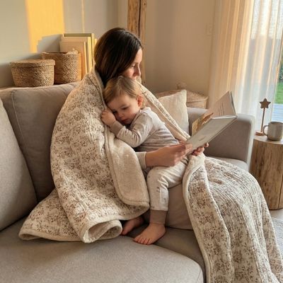 Couverture bébé beige à fleurs vintage enveloppant maman et bébé pendant moment lecture sur canapé