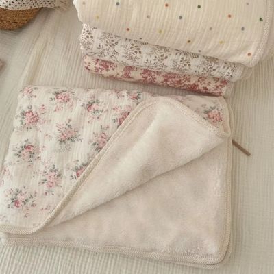Couverture bébé double face en trois motifs floraux : rose, beige et crème empilées avec hochet