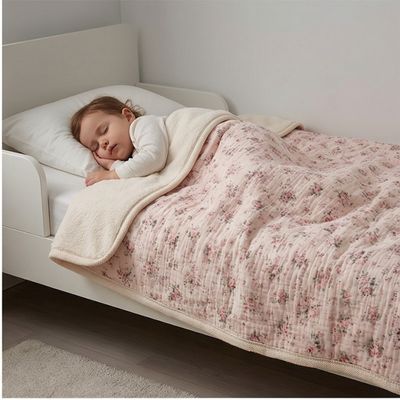  Couverture bébé à fleurs printanières utilisée par fillette dormant paisiblement dans lit enfant blanc