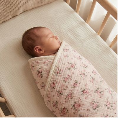 Couverture bébé à fleurs printanières en emmaillotage pour nouveau-né endormi dans lit bébé en bois