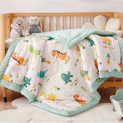 Couverture bébé texture gaufrée menthe et motifs dinosaures colorés sur lit enfant bois avec peluche