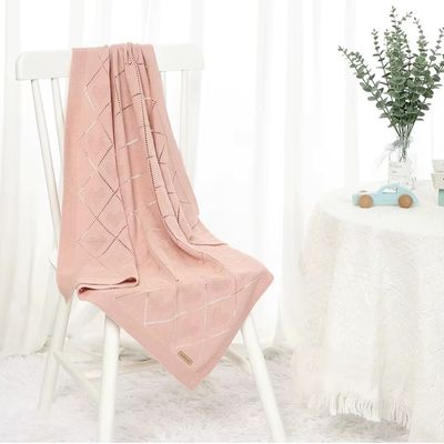 Couverture bebe Cœur de Coton rose poudré  en coton alvéolaire drapée sur une chaise blanche dans un intérieur lumineux et épuré avec décoration florale