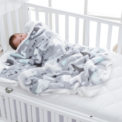 Petit garçon caché sous une couverture bébé, riant avec malice.