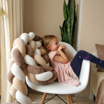 Petite fille confortablement installée dans un fauteuil blanc avec tresse de lit beige -marron foncé et blanche