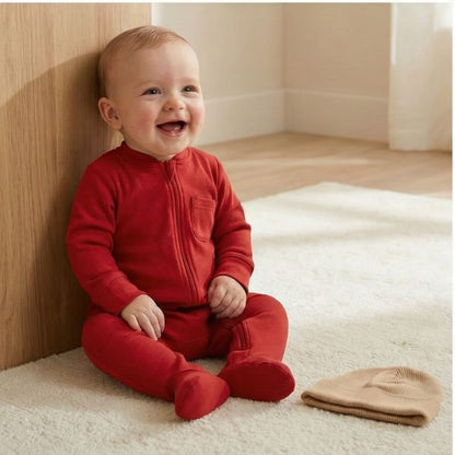 Pyjama bébé garçon rouge. Bébé tout sourire assis confortablement.