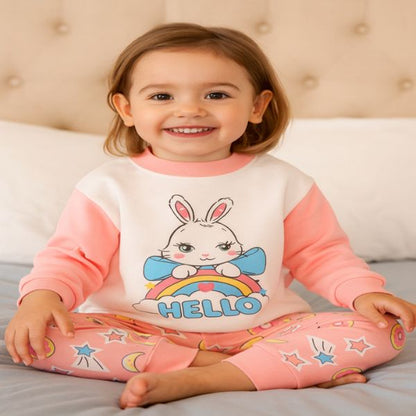 Pyjama bebe "HELLO" - Petite fille souriante assise sur le lit.