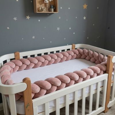 Tresse de lit de 3 m, rose poudré, décorant un lit à barreaux blanc.