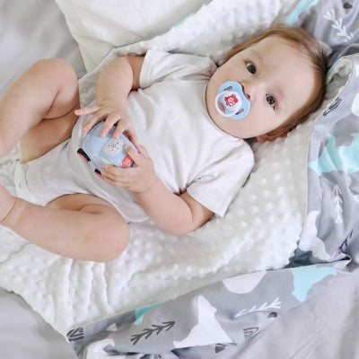 Un petit garçon est allongé sur une couverture bébé douce, le regard curieux et éveillé.