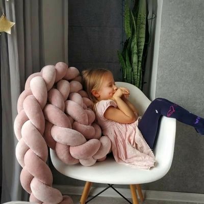 Une petite fille assise sur une chaise, avec une tresse de lit derrière le dos
